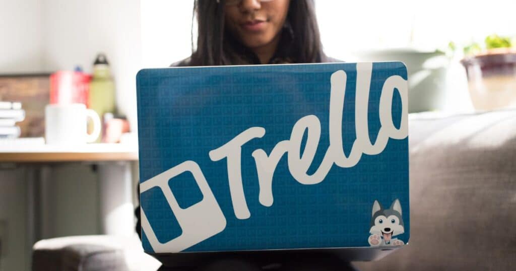 girl holding laptop with trello background on it
